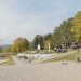 A peaceful park scene with riverside path, trees, and playground, perfect for a family outing.