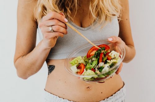 Woman in sports attire enjoys a fresh, nutritious salad, embodying a healthy lifestyle.