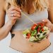 Woman in sports attire enjoys a fresh, nutritious salad, embodying a healthy lifestyle.